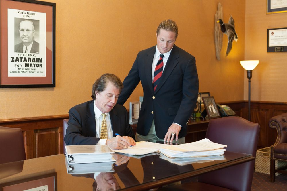 Mick Zatarain, seated, and Michael Zatarain, Jr., standing, reviewing documents in the firm's office
